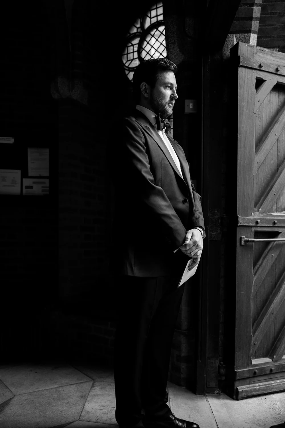 Black and white photograph of Jon waiting by the church door