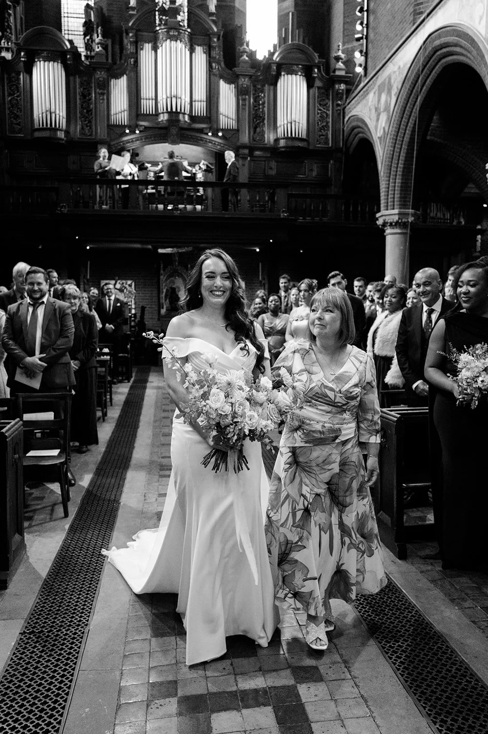 Black and white photograph of Chloe walking down the aisle at St Mary&rsquo;s Bourne Street