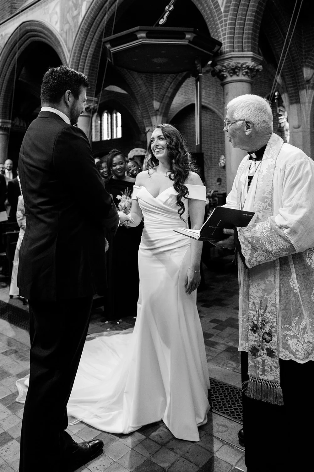 Chloe and Jon exchanging vows in front of the priest at St Mary&rsquo;s Bourne Street