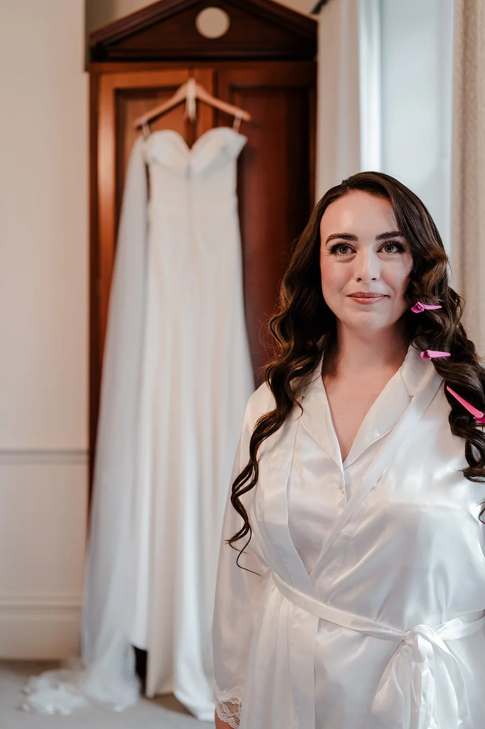 Chloe with her wedding dress hanging in the window behind her