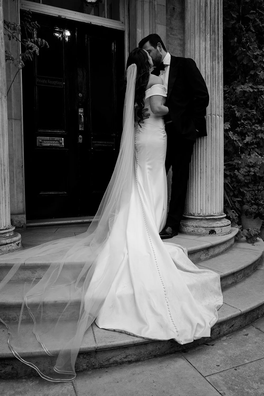 Black and white photograph of Chloe and Jon on the steps at Brunswick House