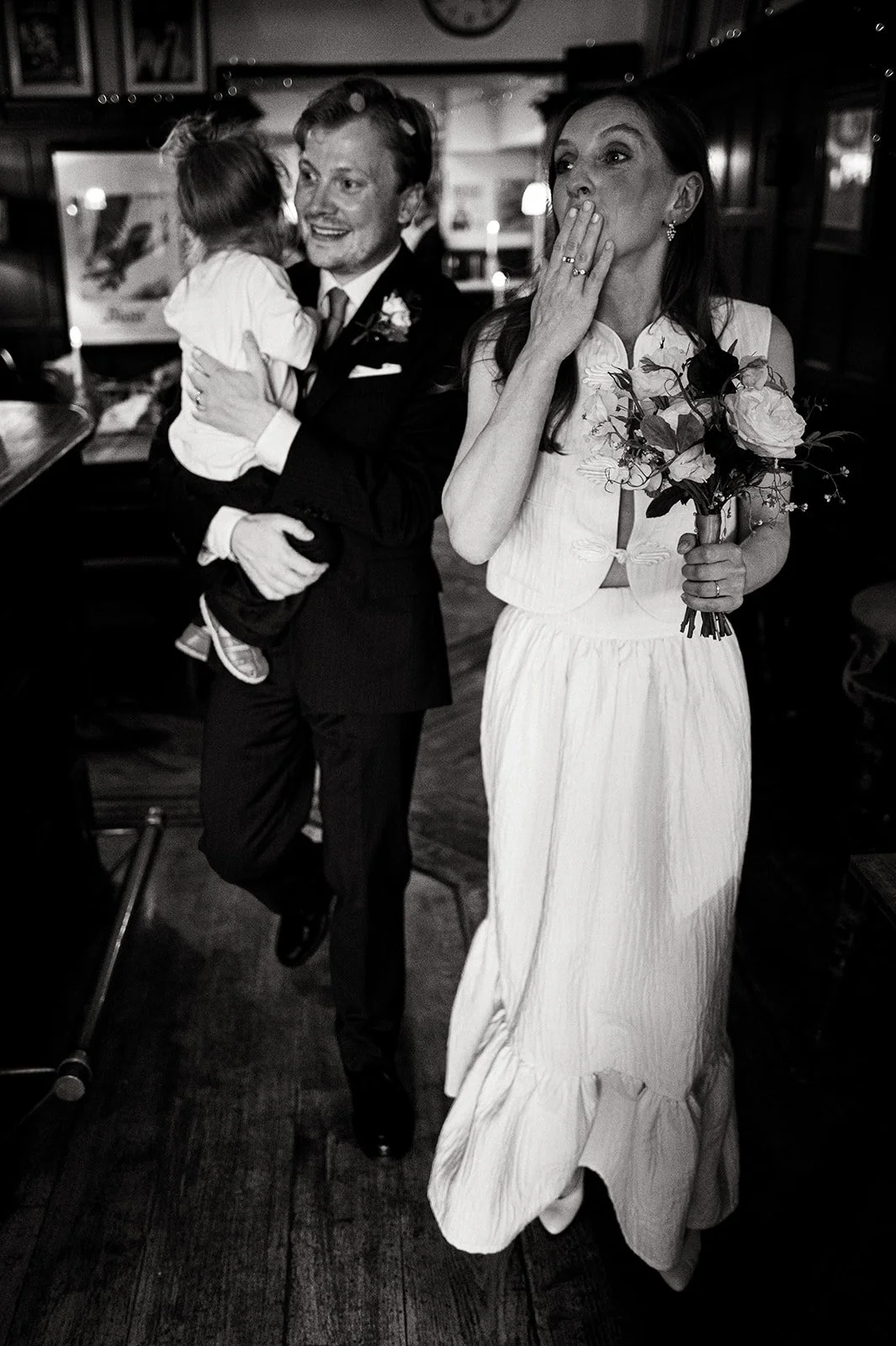 Ruby laughing with her hand to her mouth as confetti falls inside the pub