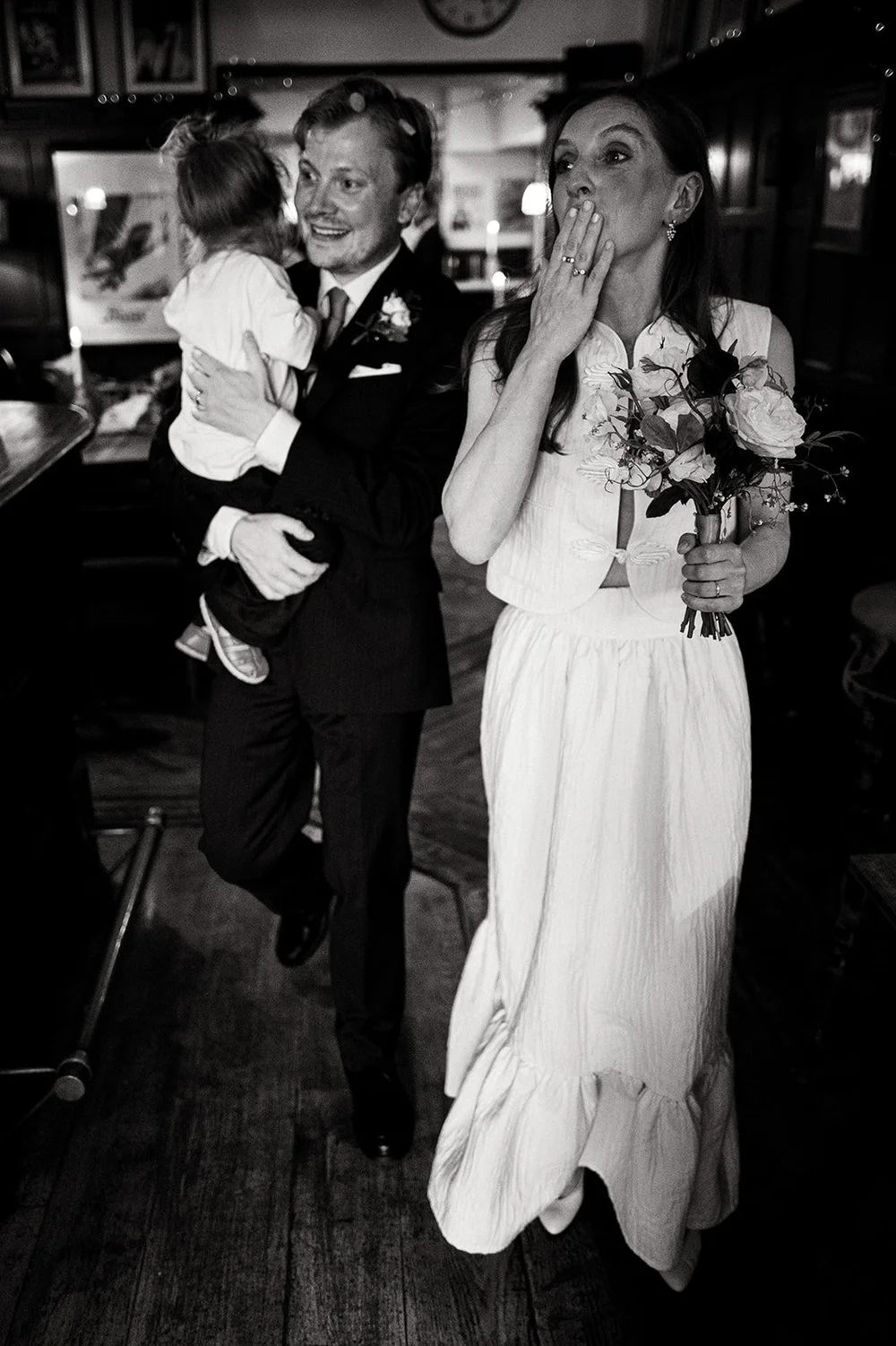 Ruby laughing with her hand to her mouth as confetti falls inside the pub