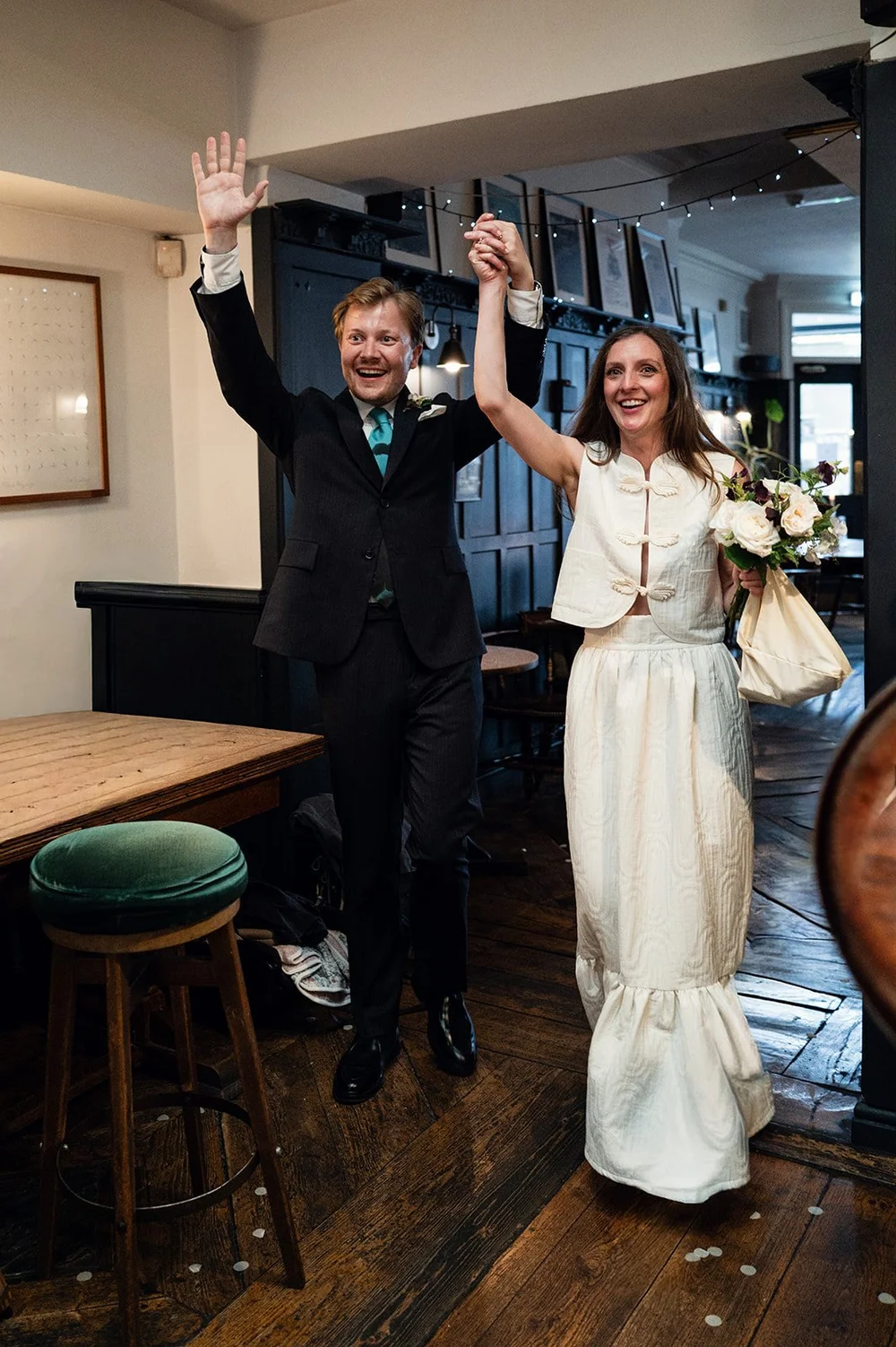 Patrick and Ruby raising their arms as they come in for the wedding breakfast