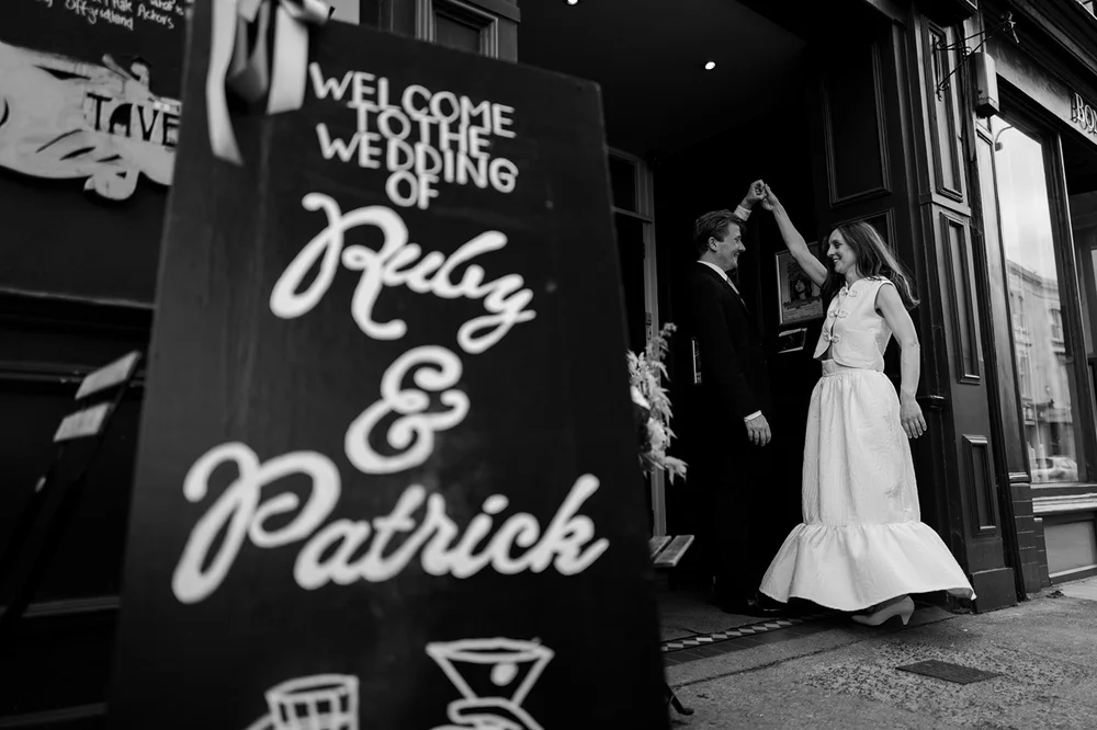 Black and white photograph of a guest beside the wedding chalkboard