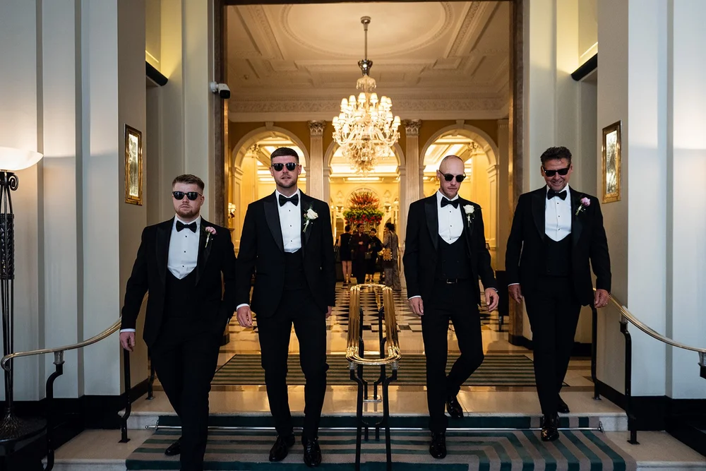 Joe and his groomsmen in the chandeliered corridor at Claridge&rsquo;s in Mayfair