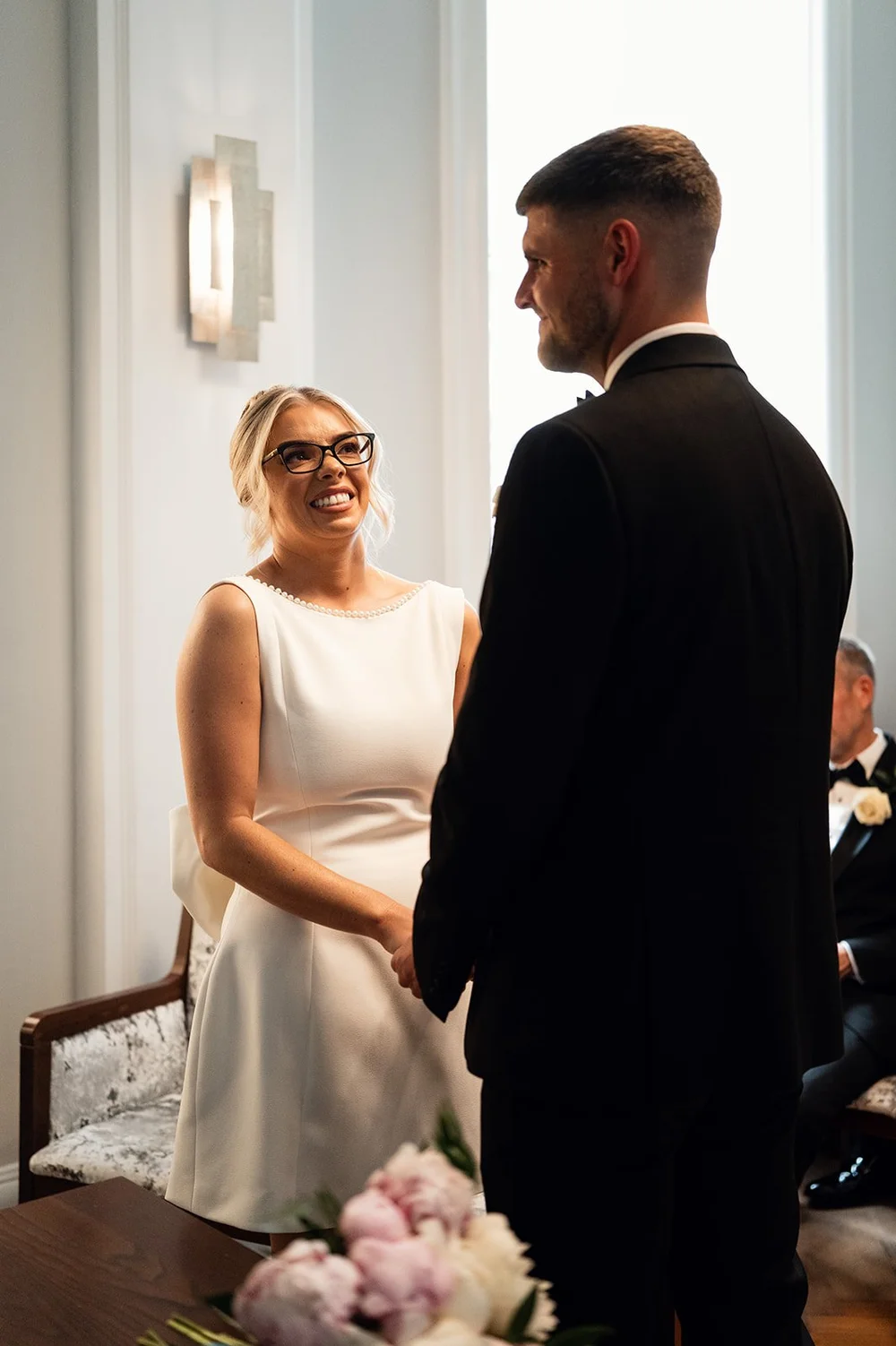 Charley and Joe facing each other during their ceremony at Chelsea Old Town Hall