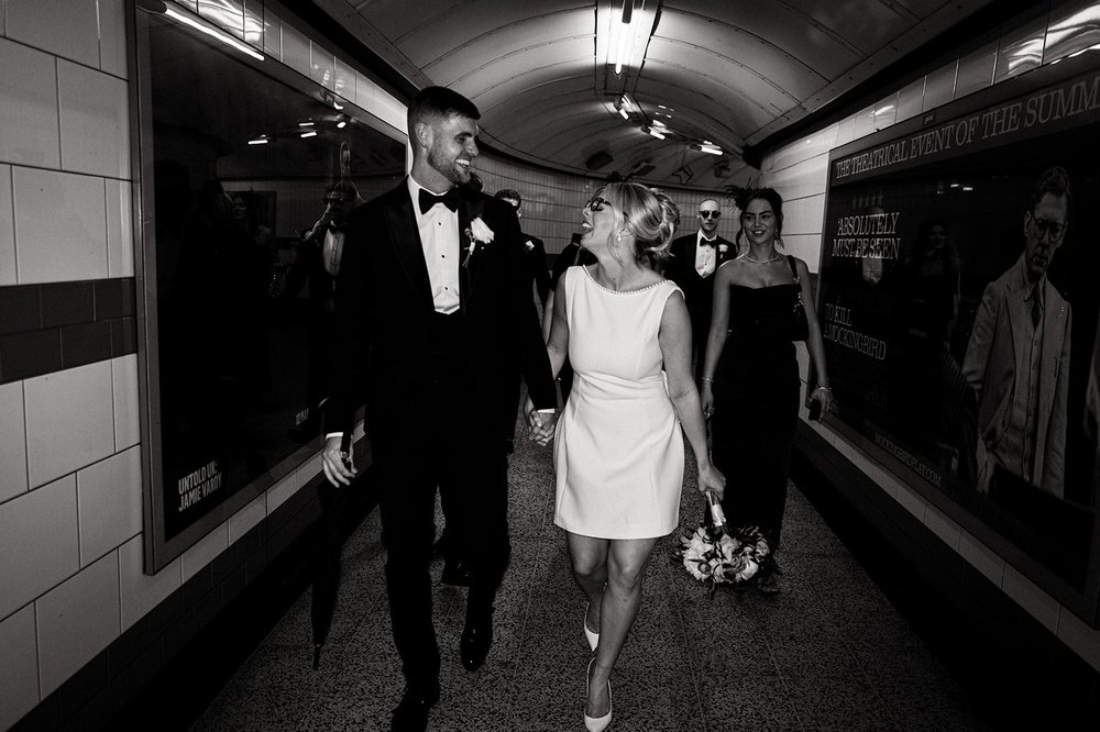 Charley walking through the tiled passageway of the underground in her wedding dress