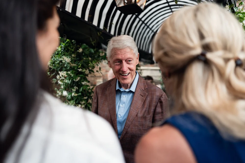 Bill Clinton chatting with guests at his birthday celebration at Kensington Roof Gardens, London, photographed by Oliver Holder
