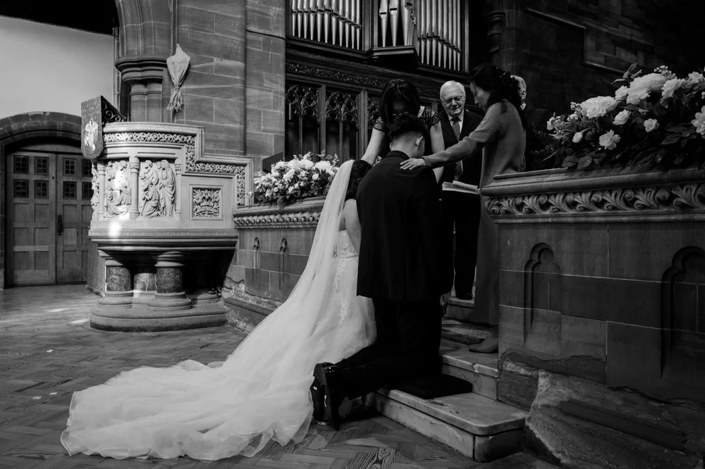 Bride and groom on the steps of a city church, her veil spread out behind her