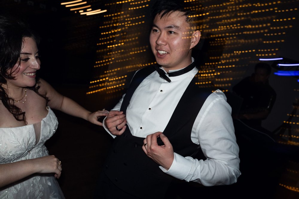 Bride and groom dancing together under warm festoon lights