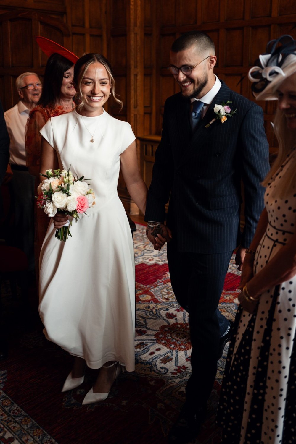 Bride and groom walking back down the aisle surrounded by their guests