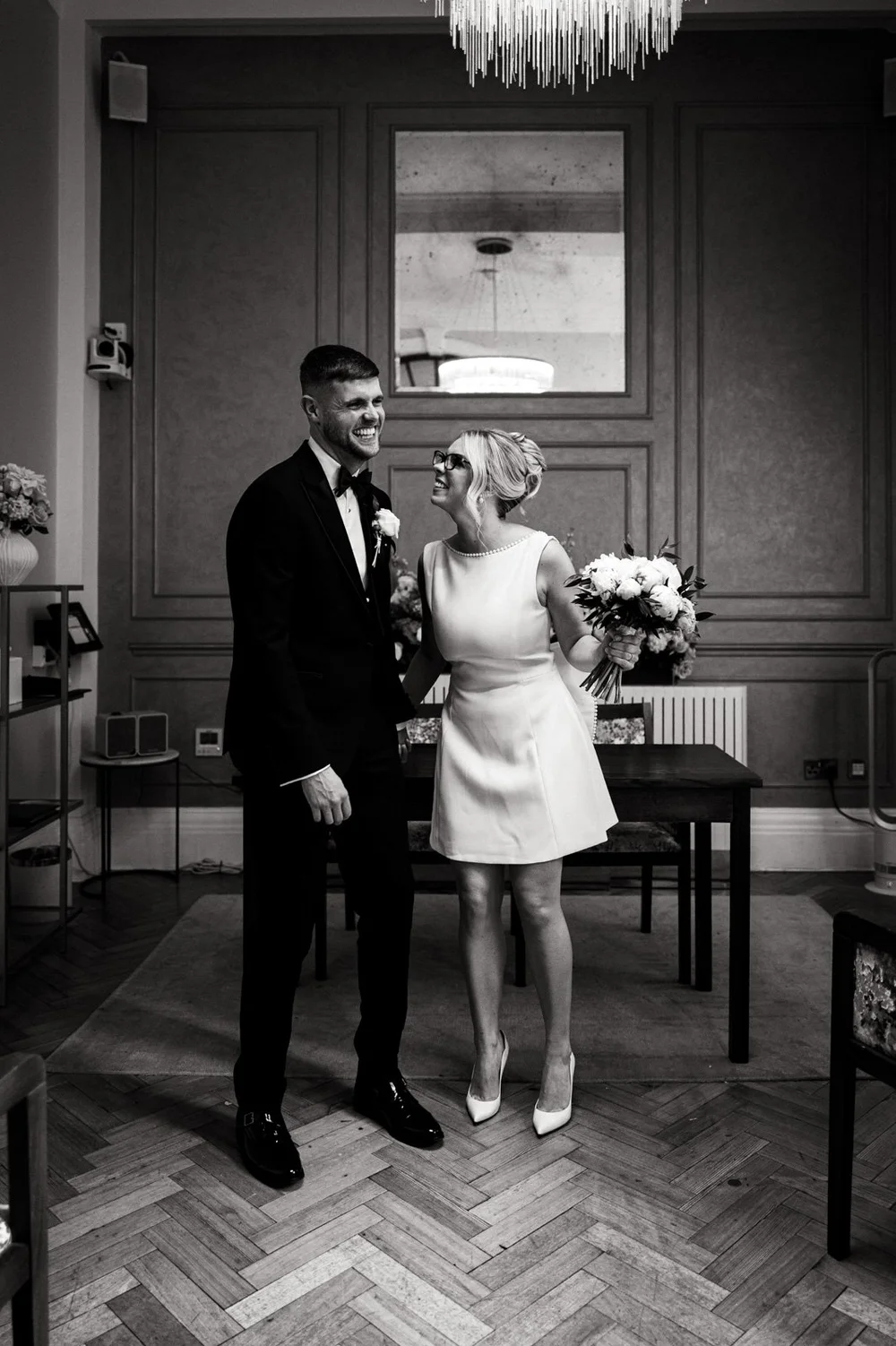 Bride and groom laughing together in a quiet ceremony room before the guests arrive