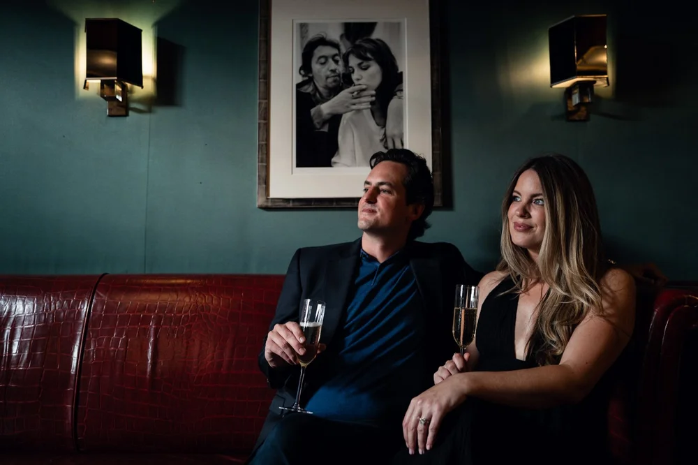 Two guests sitting back on a leather banquette with champagne