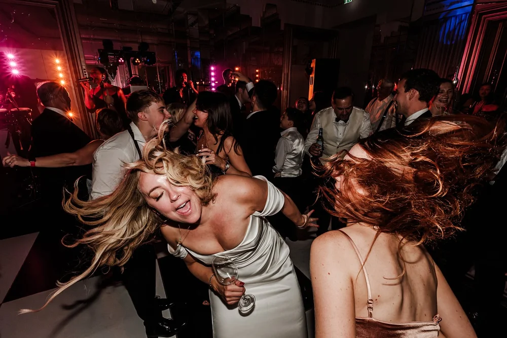 Guests dancing with hair flying under pink lights on the dance floor