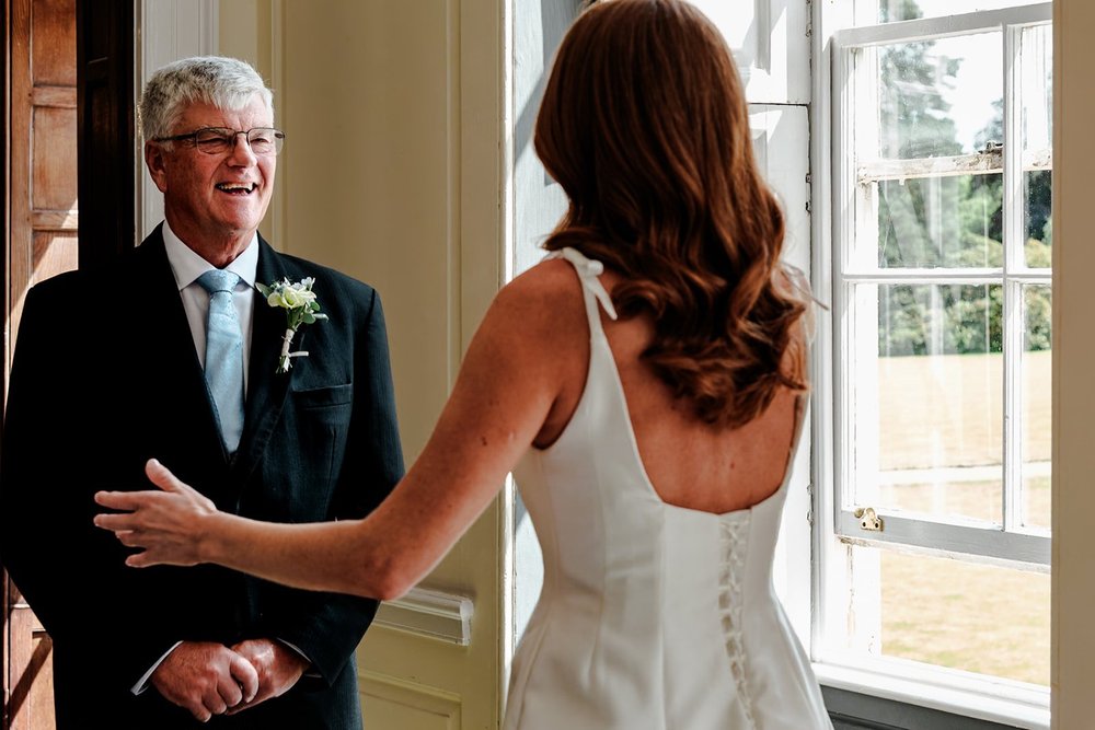 The bride&rsquo;s father seeing her in her dress for the first time, arms open