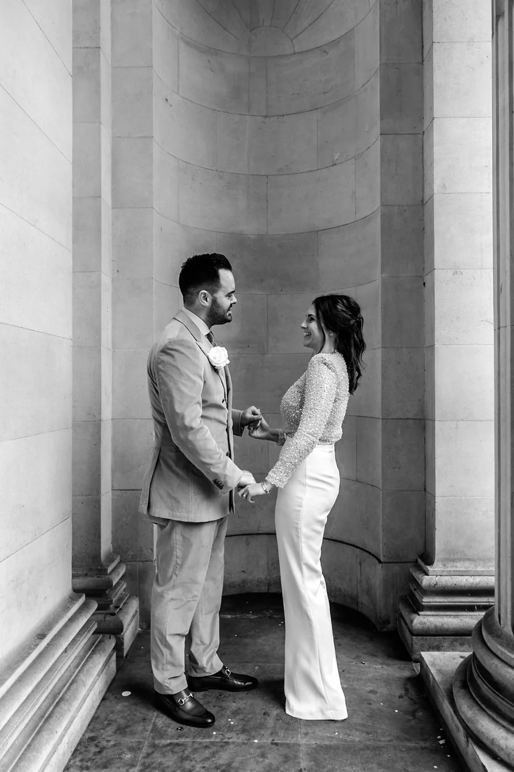 Bride and groom holding hands between tall stone columns