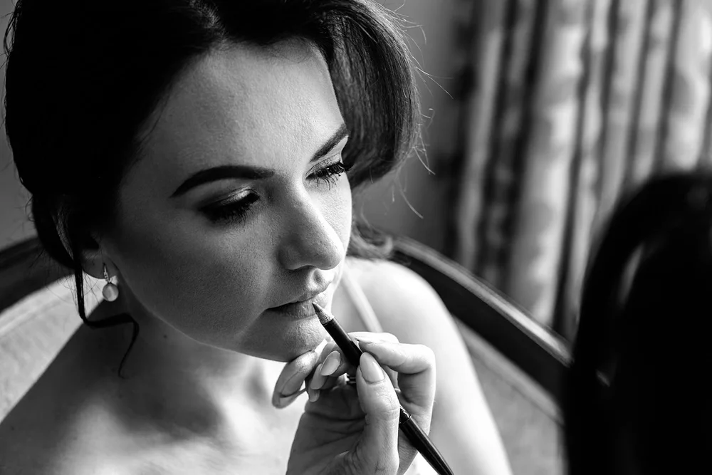 Bride having her lipstick finished on the wedding morning