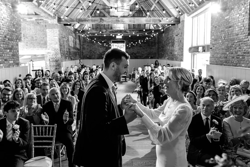 Couple exchanging vows in a packed barn lined with guests