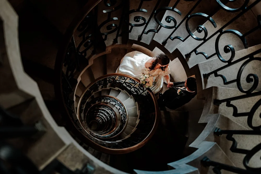 Looking down a spiral staircase at the bride on the floor below