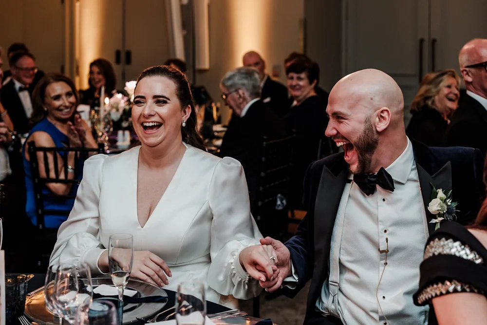 Bride and groom laughing together during the speeches