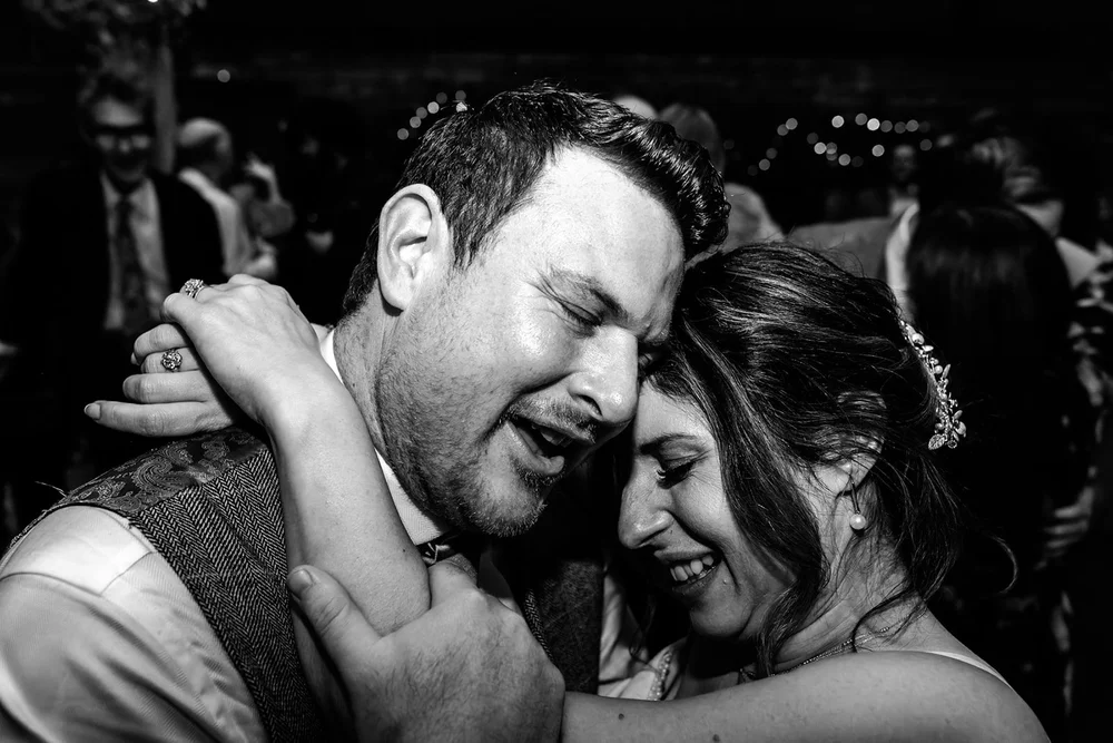 Bride and groom holding each other close on the dance floor