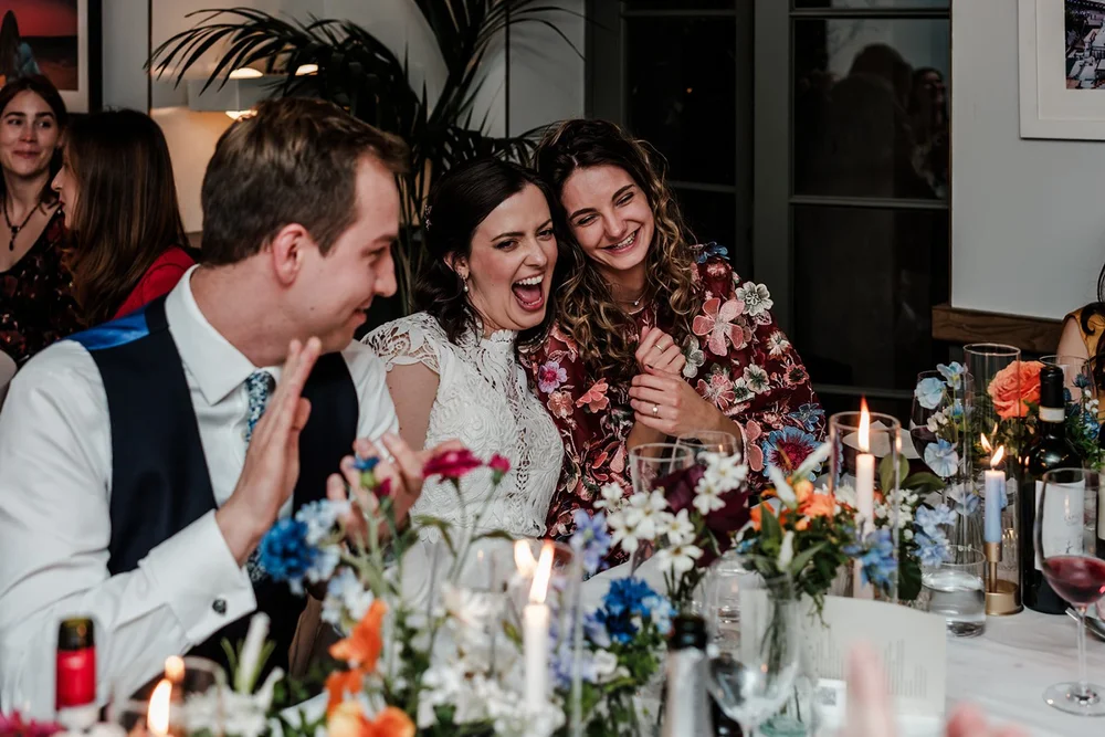Guests laughing along a table filled with flowers and candles