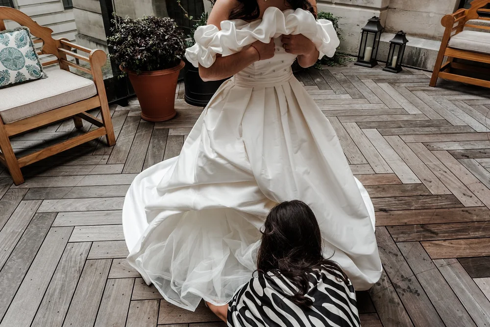 Bride sitting on a herringbone floor in her dress, laughing