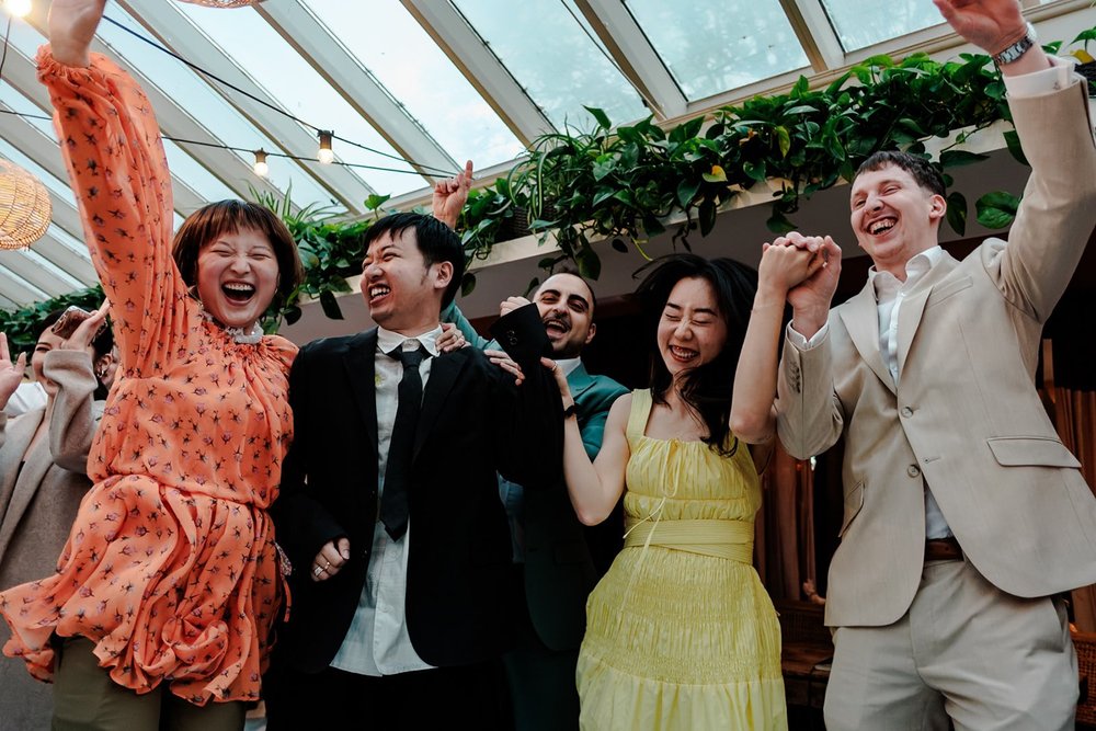 Guests cheering with their arms raised in a glasshouse