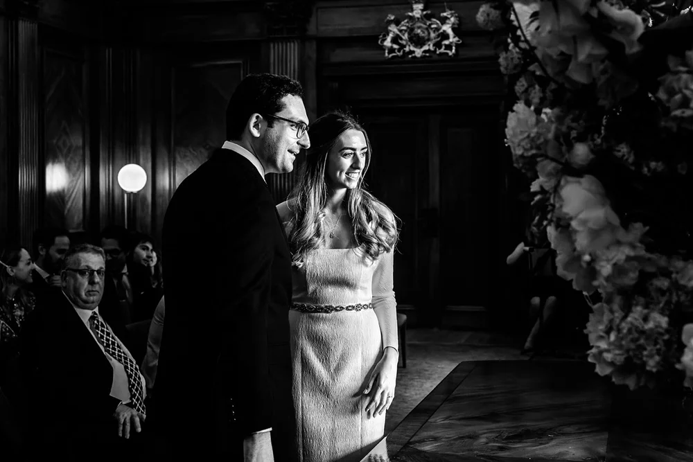 Bride and groom dancing closely beneath a flower arch
