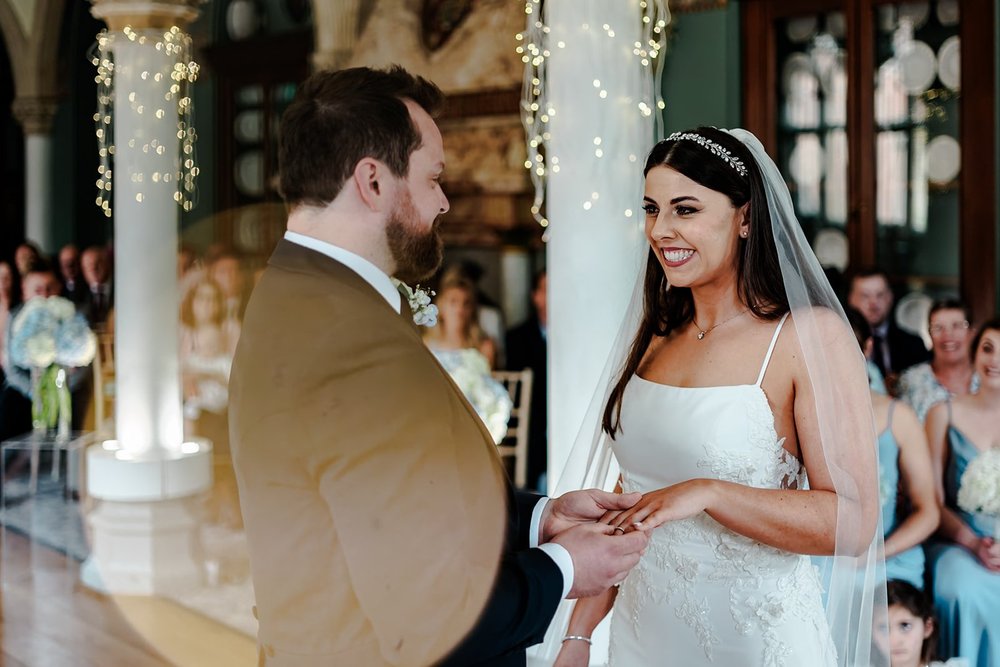 Bride and groom exchanging rings beneath fairy lights