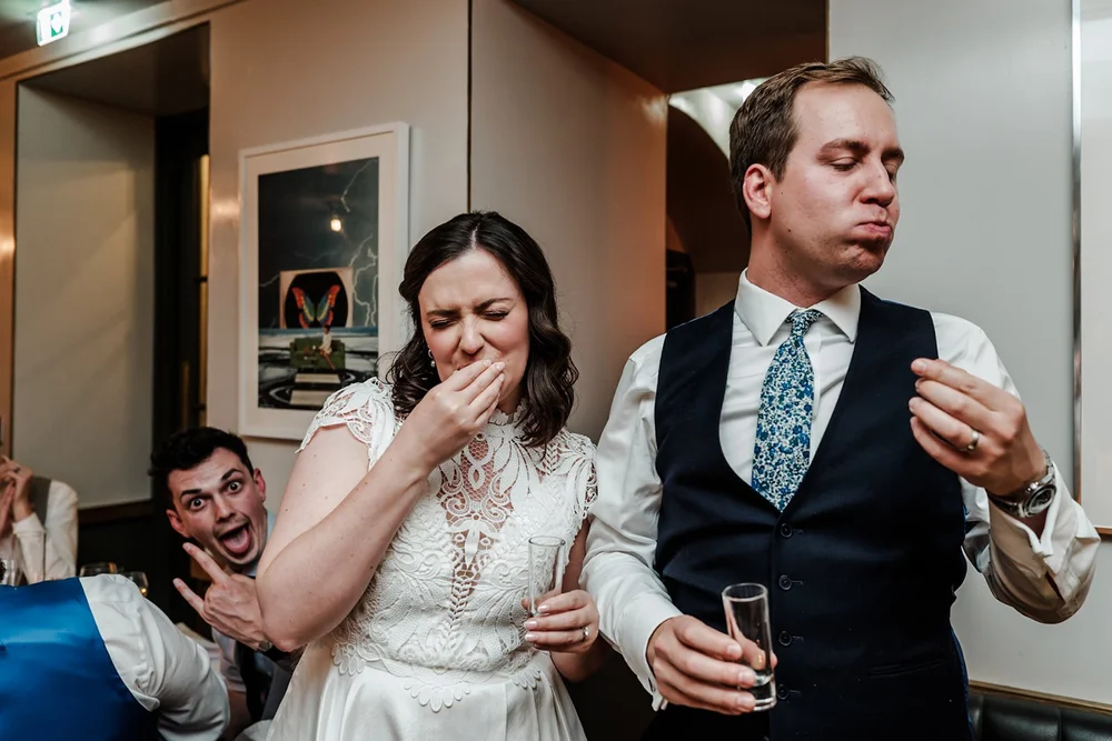 Bride laughing with a guest photobombing behind her