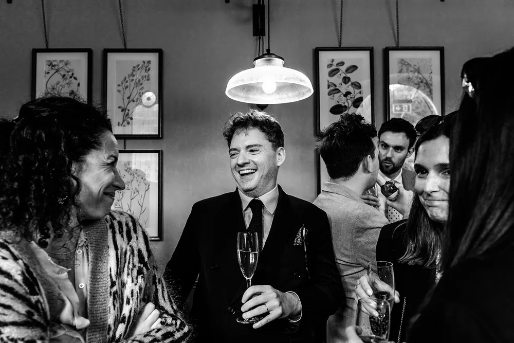 Guests laughing together with drinks under a pendant lamp