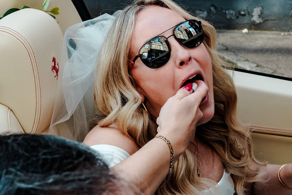 Bride in sunglasses and veil in the back of the wedding car