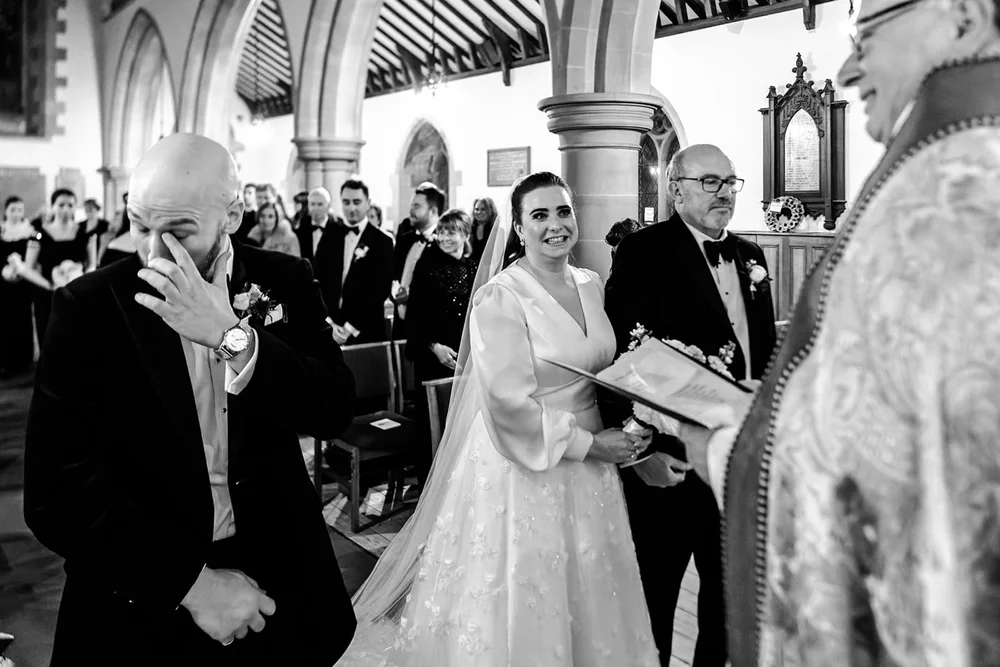 Bride and her father at the church door as the priest waits