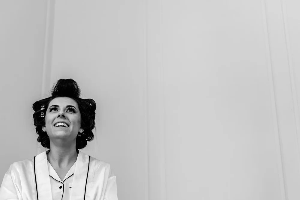 Bride in pyjamas and hair rollers laughing on the wedding morning