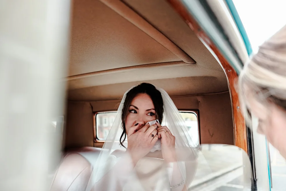 Bride overcome with emotion in the back of the wedding car