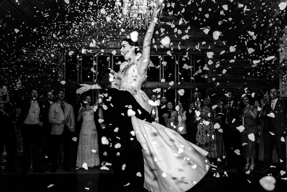 Bride spinning in a confetti shower surrounded by her guests