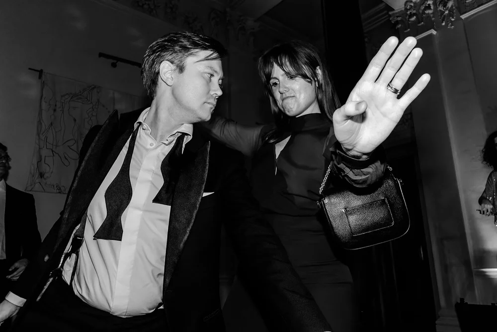 Guests dancing, one waving a hand towards the camera