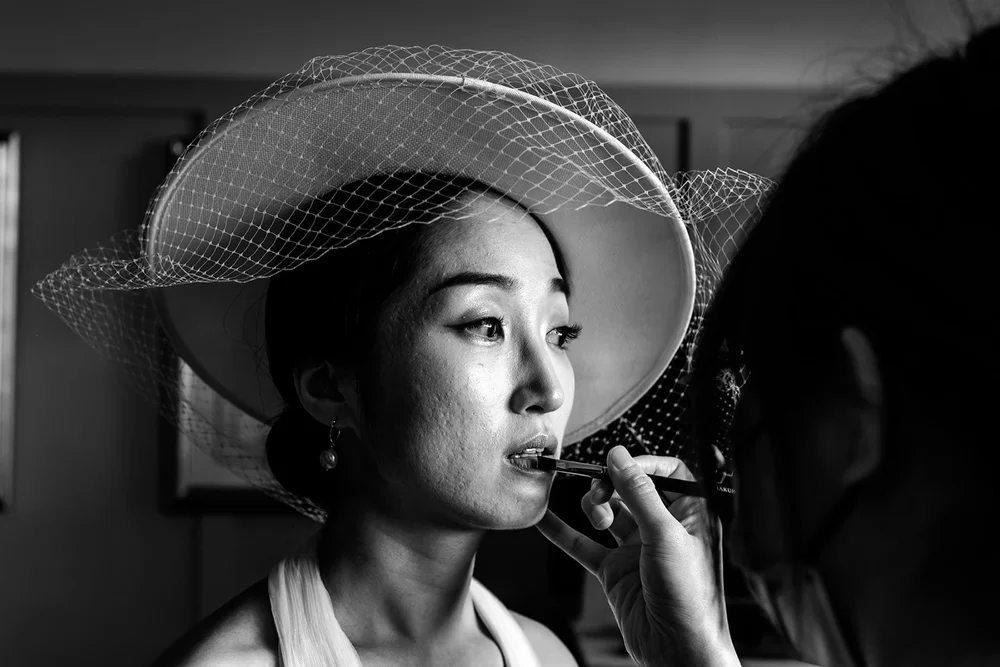 A guest in a birdcage hat applying her lipstick