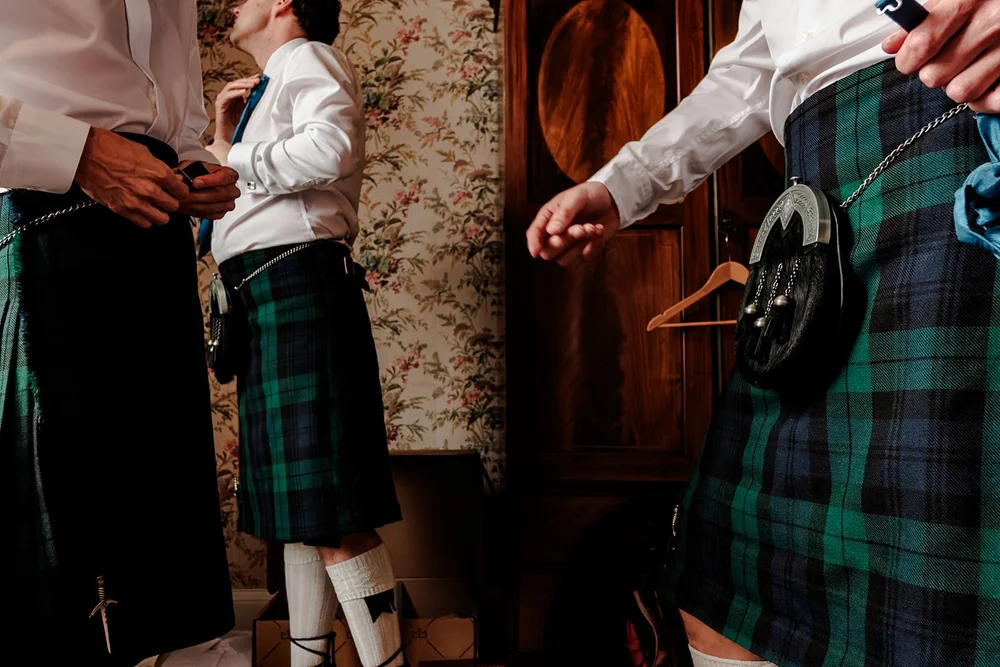 Groomsmen in tartan kilts getting ready together before the ceremony