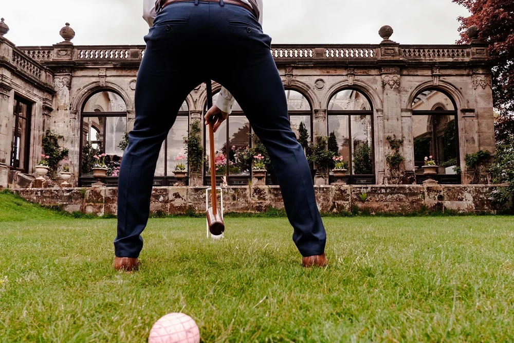 A guest playing garden games on the lawn in front of a country house orangery
