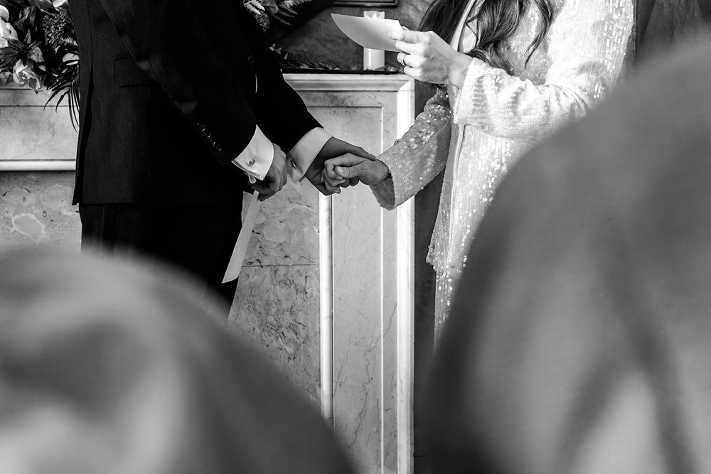 Close up of the couple&rsquo;s hands as they cut the wedding cake