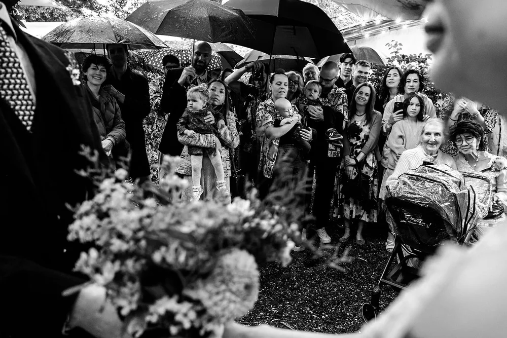 Guests packed together under umbrellas in the rain to watch the ceremony