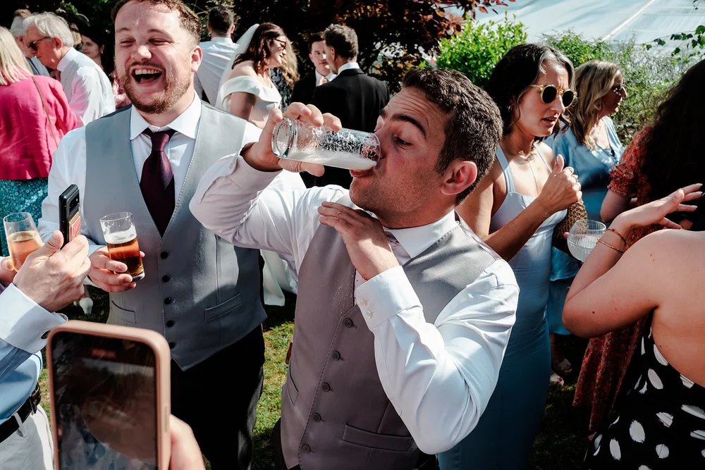 Guests helping each other finish a drink outdoors after the ceremony