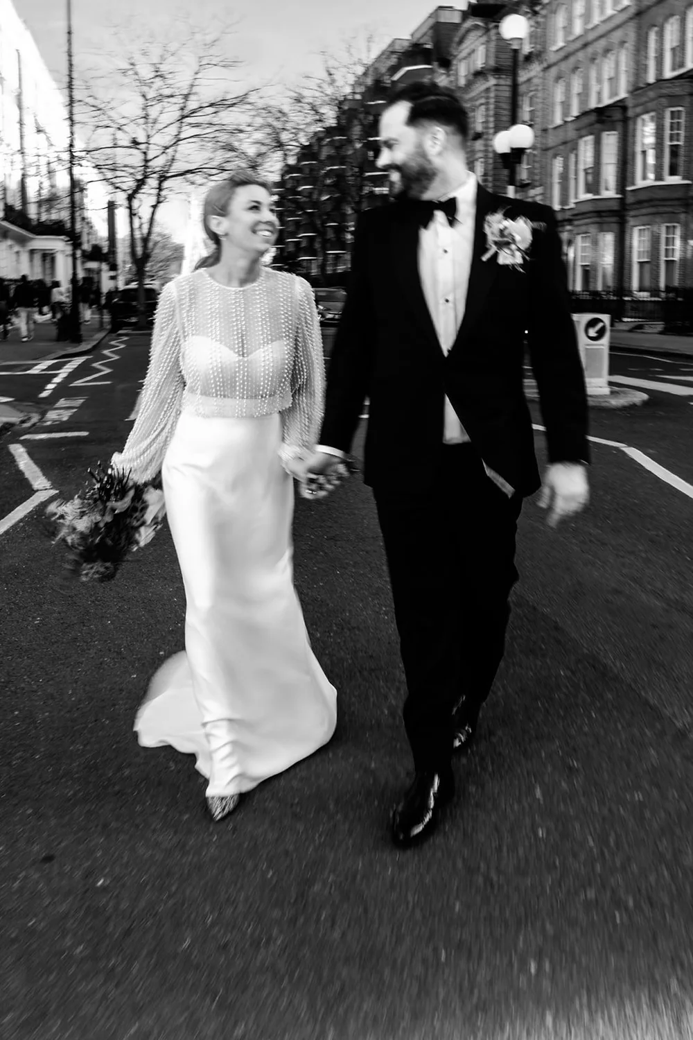 Bride and groom walking hand in hand down a London street