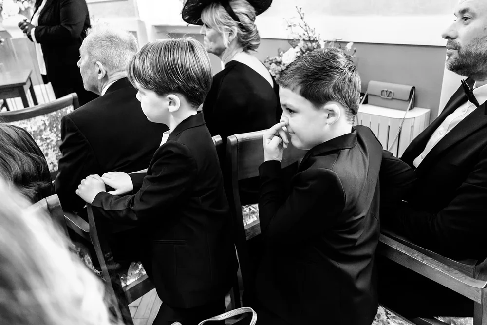 Two boys in black tie fidgeting in the pews during the ceremony