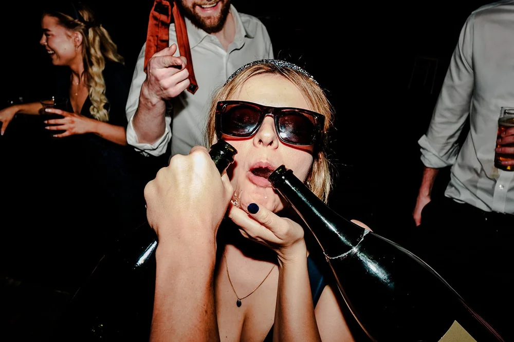 A guest in sunglasses drinking straight from the bottle on the dance floor