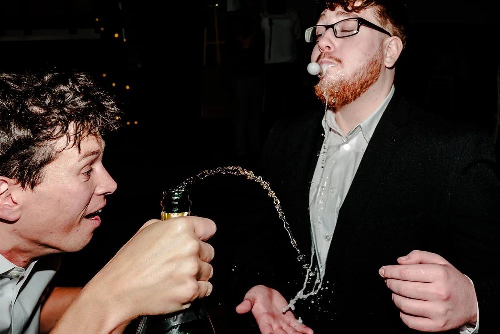 A guest spraying beer over another guest during the evening party