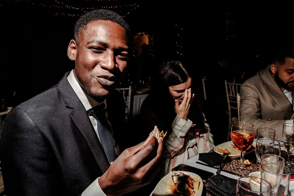 A guest laughing at the dinner table over a plate of food